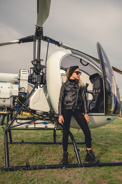 Teenage girl in black clothes and sunglasses looking into distance near helicopter