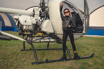 Teenage girl in black clothes posing near helicopter