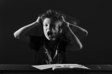 tired teenage schoolboy rage shouts, waves hands sitting table front book. concept childhood, home...