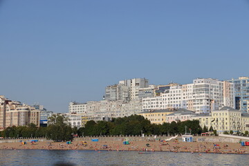 A lot of people on the beach in Samara against the background of the embankment and residential buildings, August 2021