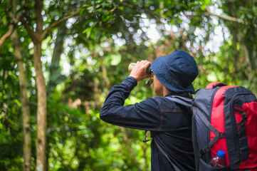 Tourists watching bird hornbill and monkey with binoculars in the tropical forest. Khao Yai...