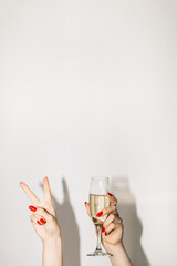 Party fun. Happy Christmas. Festive celebration. Advertising background. Elegant female hand holding champagne glass showing victory sign pointing copy space isolated white.