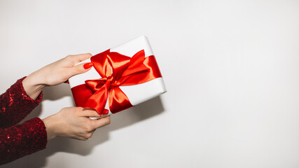 Christmas gift. Happy celebration. Greeting congrats. Advertising background. Elegant female hands holding present box red ribbon isolated white copy space.