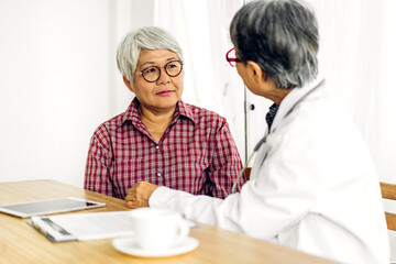 Fototapeta premium Senior woman doctor wearing uniform with stethoscope service help support discussing and consulting talk to sick woman patient about checkup result information with tablet computer in hospital