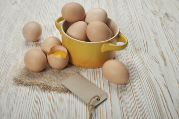 Bowl of raw chicken eggs on the wooden background