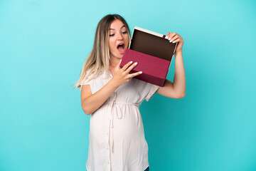 Young Romanian woman isolated on blue background pregnant and holding a gift with surprised expression