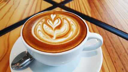Hot Latte in white cup place on wood table.