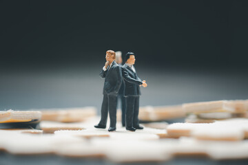 Miniature businessman standing on wood jigsaw found business obstacle come from many directions.