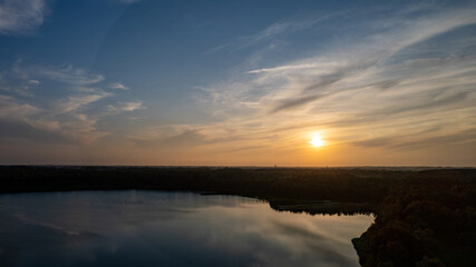 Aerial view shot by a drone of a beautiful dramatic and colorful sunset at coast of the lake. Nature landscape. Nature in Europe. reflection, blue sky and yellow sunlight. landscape during sunrise or