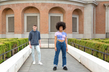 Fototapeta premium Young caucasian man behind afro woman posing serious