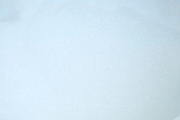 Obraz premium White bubbled foam in bathroom on blue tile background. Preparing to the bathing. Relaxed bath for people. Texture, background for video.