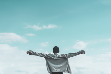 Copy space of man rising hands on blue sky white clouds abstract background. Freedom feel good and travel adventure concept.