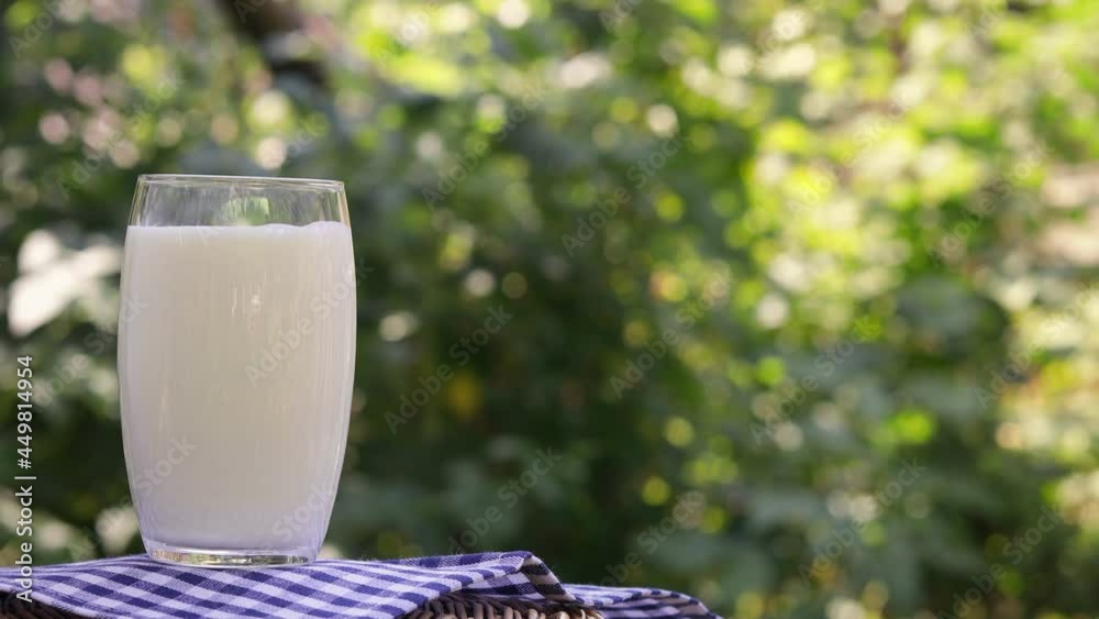 Poster milk pouring from jug into glass outdoors