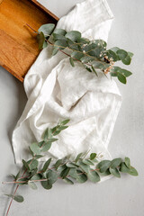 Background with a composition of eucalyptus flowers, fabric and a wooden tray. Top view, flat