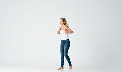 Fototapeta na wymiar pretty woman in jeans movements dance barefoot light background