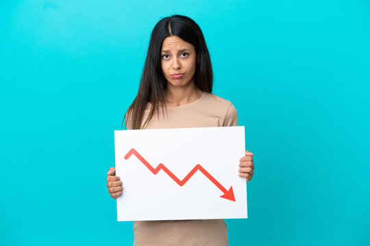 Young woman over isolated background holding a sign with a decreasing statistics arrow symbol with sad expression