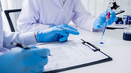 Medical or scientific researcher or man doctor looking at a test tube of clear solution in a laboratory