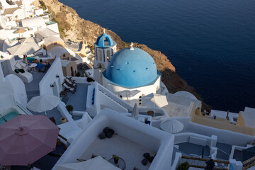 View from viewpoint of Oia village with blue dome of  greek orthodox Christian church and traditional whitewashed greek architecture.  Santorini, Greece