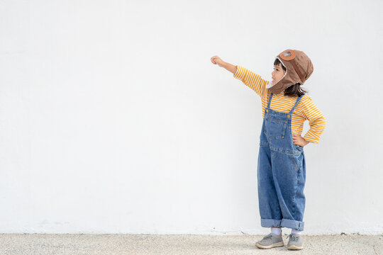 A Little Child Girl In An Astronaut Costume Is Playing And Dreaming Of Becoming A Spaceman. On White Background