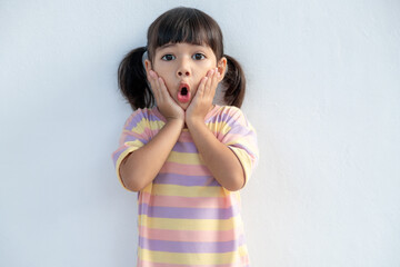 Portrait of surprised cute little toddler girl child standing isolated over white background. Looking at the camera. hands near open mouth