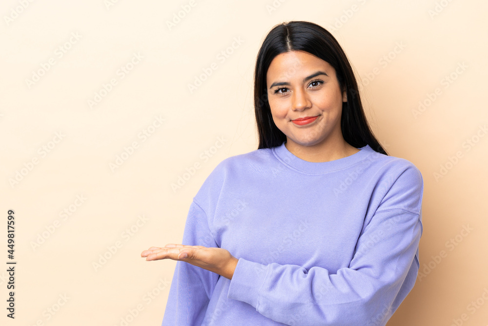 Wall mural Young latin woman woman over isolated background presenting an idea while looking smiling towards