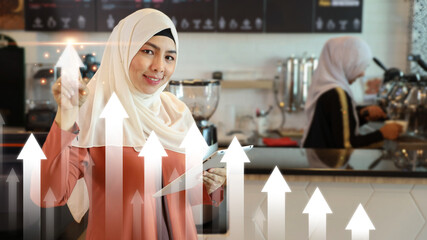 Asian muslim businesswoman pointing arrow up of future business growth graph plan or chart financial goals with coffee shop counter background