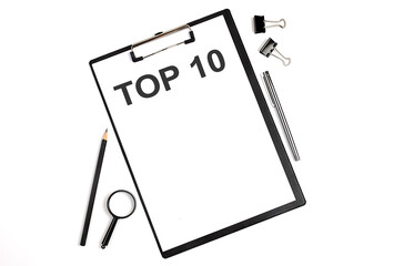 On a white background magnifier, a pen and a sheet of paper with the text TOP 10 , . Business concept