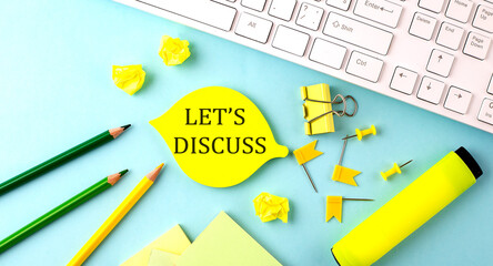 Text sign showing LET'S DISCUSS with office tools and keyboard on blue background