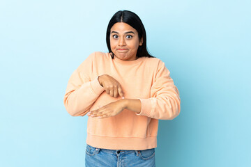 Young latin woman woman isolated on blue background making the gesture of being late