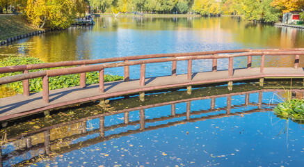 Autumn landscape with wooden bridge over the pond in the park
