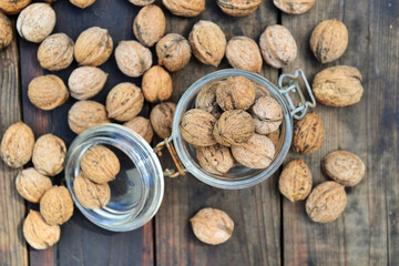 walnuts in a glass jar among others on wooden table