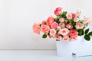Bouquet of pink roses on a light wooden background.