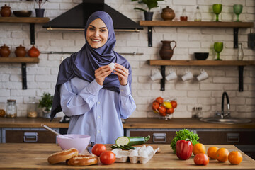 Cheerful Arabian woman holding an egg and giving a broad smile to the camera