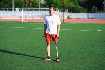 Portrait of young caucasian male athlete brunette with prosthetic leg on the stadium on the field