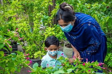 Asian mothers and children wearing safety masks are spending a good time in the green garden. Covid-19 pandemic, Lockdown, and home quarantine time safety concept. Educational and safety concept.