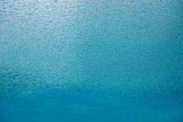 The surface is blue water with ripples from the light wind and reflection. Abstract water perfect background.