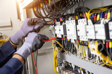 Electrician engineer tests electrical installations and wires on relay protection system. Adjustment of scheme of automation and control of electrical equipment.