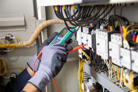 Electrician engineer tests electrical installations and wires on relay protection system. Adjustment of scheme of automation and control of electrical equipment.