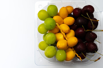 Colorful fruits of yellow raw of date palm fresh,green graps and cherry with water droplets are sweet healthy fruit in food box and  isolated on white background.