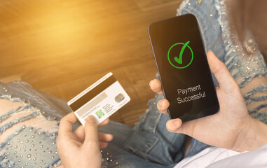 Businesswoman paying her bills with smartphone and credit card. Mobile phone with payment successful inscription screen and credit card in hand. Work from home concept photo