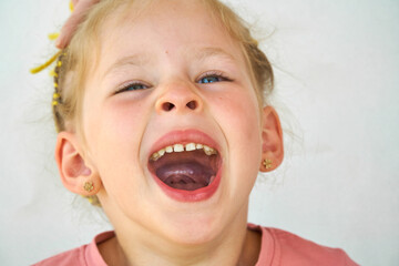 yawns child. Girl laughs close-up of the face on a white background. A little girl show tongue...