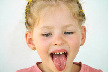 Cheerful child. Girl laughs close-up of the face on a white background. A little girl show tongue throat. portrait with wide open mouth and protruding tongue. with clear view pulls out long tongue