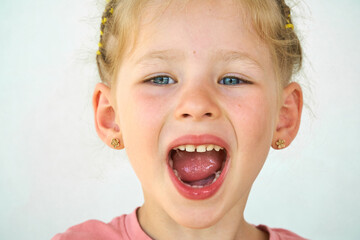 Cheerful child. Girl laughs close-up of the face on a white background. A little girl show tongue throat. portrait with wide open mouth and protruding tongue. with clear view pulls out long tongue