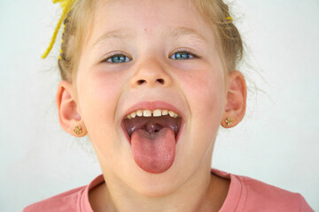 Cheerful child. Girl laughs close-up of the face on a white background. A little girl show tongue...