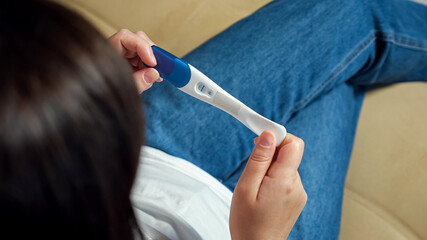 Unrecognizable woman turns a positive pregnancy test to find out the result.