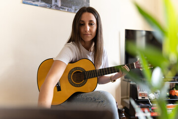 Attractive young female searching on the internet for tutorials to learn at home new chords and how...
