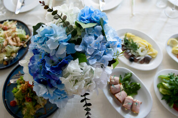 A table with a bouquet and food for the reception of guests. Festive design of the dining table at a banquet party.
