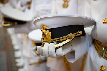 A white naval cap in the hand of a Navy officer. The dress uniform of the highest personnel of the Russian Navy. - obrazy, fototapety, plakaty