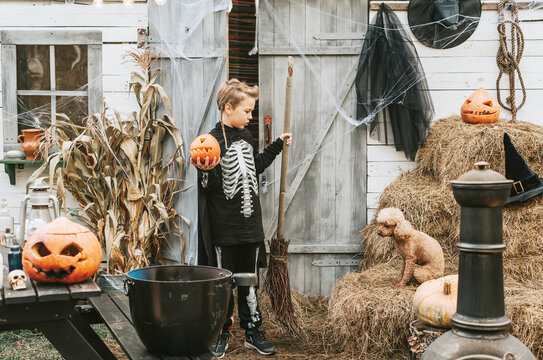 boy in a skeleton costume with a dog on the porch of a house decorated to celebrate a Halloween party