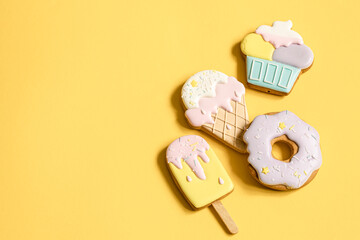 Colorful glazed gingerbread cookies on yellow background copy space.